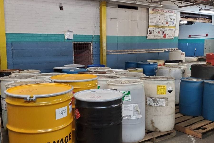 large barrels containing hazardous materials sit on pallets awaiting removal