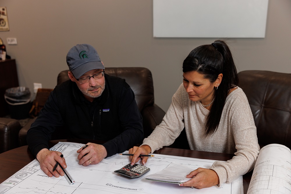 Consultants using calculator and blueprint to design solutions