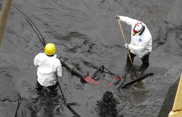 Crew removing sludge from industrial tank