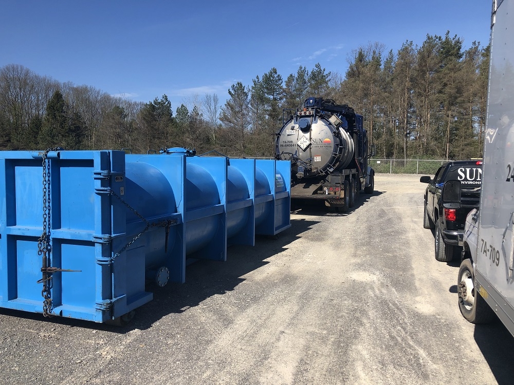 Vacuum truck positioned near large containment unit